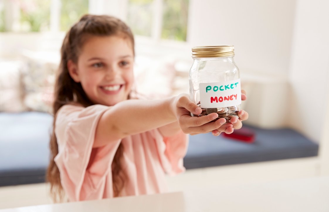 Girl Saving Pocket Money In Glass Jar At Home